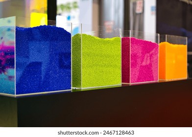 Granulates presented in glasses on a stack during the 28th International Fair of Plastics and Rubber Processing PLASTPOL in Kielce. Selective focus, green, red, yellow, blue, multicolor.