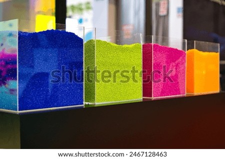 Granulates presented in glasses on a stack during the 28th International Fair of Plastics and Rubber Processing PLASTPOL in Kielce. Selective focus, green, red, yellow, blue, multicolor.