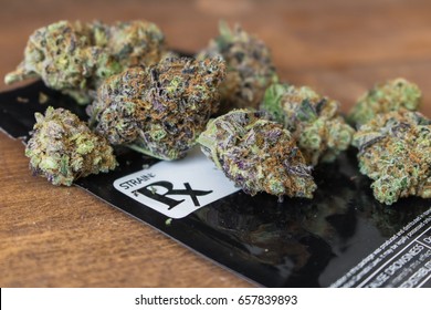 Grape Ape Strain / Medical marijuana buds with black prescription bag on wood.