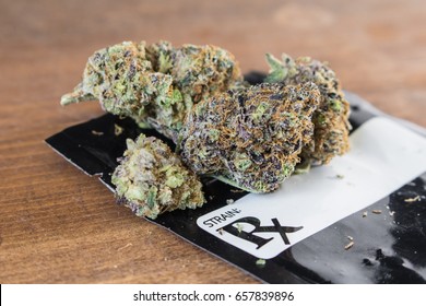 Grape Ape Strain / Medical Marijuana Buds With Black Prescription Bag On Wood.