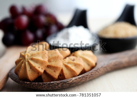 Grape cookies on woodenspoon with sugar , grape ,flour and woodentable background