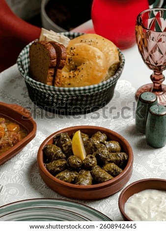 Grape dolma in ceramic pot, bread, empty glass