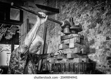 Récolte de raisins: viticulteur âgé travaillant sur une presse à vin vintage. Arrière-plan vintage 