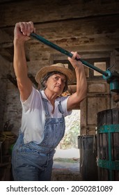 Grape harvest: Old woman winemaker  working on a traditional winepress for the must pressing. Old winery background