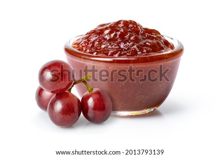 Grape jam in glass jar with red grapes isolated on white background.