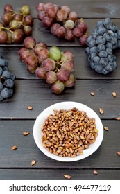 Grape Seed Oil And Grape On Black Wooden Table.