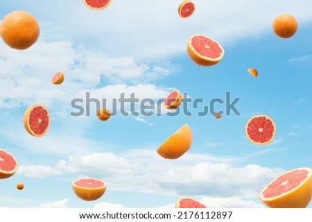 Grapefruit citrus flying. Blue sky with clouds in the background. Surreal aesthetic fruit outdoor summer food concept.