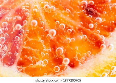 Grapefruit close-up in liquid with bubbles. Slice of blood red ripe grapefruit in water. Part of set.