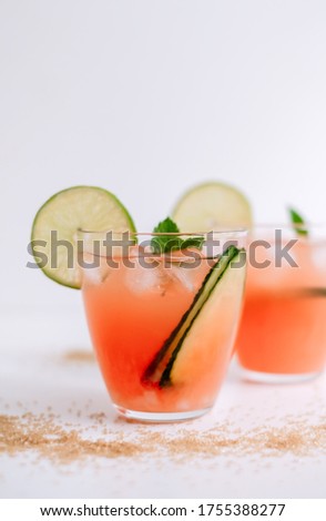 Grapefruit cocktail, lemonade with lime, mint and pieces of ice on a white table with cane sugar.