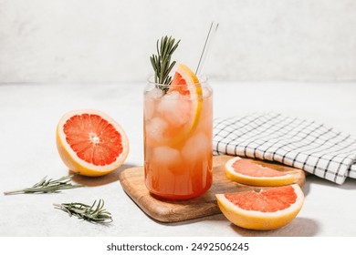 Grapefruit cocktail with rosemary garnish in a glass, served on a wooden cutting board. Vibrant, refreshing drink perfect for summer menu or cocktail recipes. Greyhound, lemonade, paloma, mocktail - Powered by Shutterstock