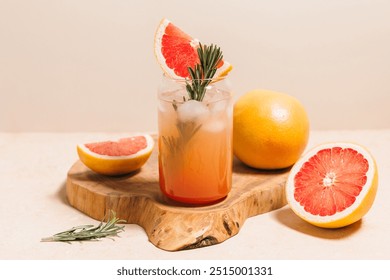 Grapefruit cocktail with rosemary garnish in a glass, served on a wooden cutting board. Vibrant, refreshing drink perfect for summer menu or cocktail recipes. Greyhound, lemonade, paloma, mocktail