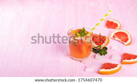 Grapefruit cocktails with mint and ice. Cold summer citrus fresh beverage on light pink wooden background