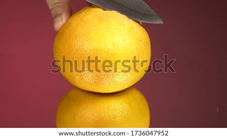 Grapefruit fillets and half of a red grapefruit a on the mirror and red background