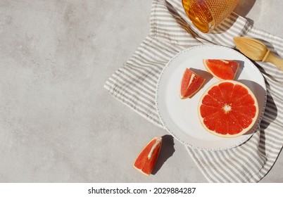 Grapefruit juce still life mockup. Slices of juicy grapefruit on a white plate and striped linen napkin top view on gray concrete table background in sunlight. Making juice food concept. copy space.