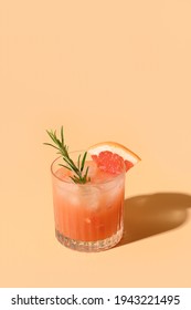 Grapefruit juice garnish rosemary sprig on color beige background. Mocktail Paloma. Close up. Vertical format.