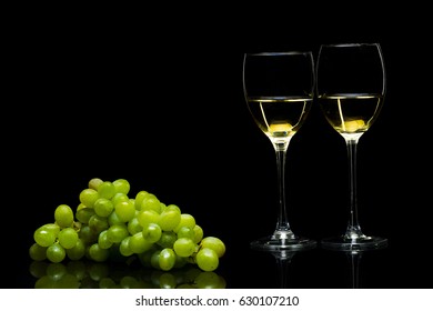 Grapes and three glasses for wine on a black background, studio light