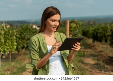 Grapes in a vineyard being checked by a female vintner. Woman using tablet to check grapes - Powered by Shutterstock