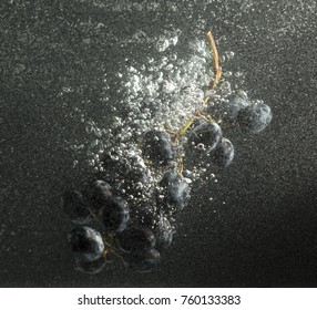grapes in water with splashes on a black background