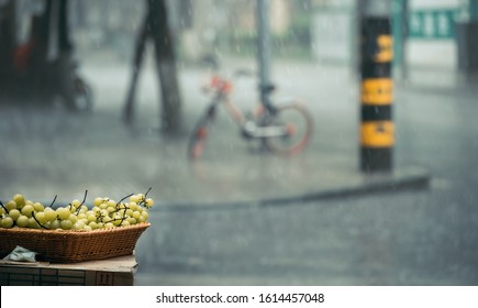 Grapes In A Wicker Basket For Sale From A Fruit Shop Outdoor Display During A Monsoon Rain In China