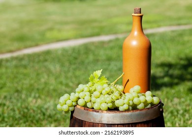 Grapes And Wine Bottle On Wine Barrel On Outdoor Sunny Garden With Copy Space