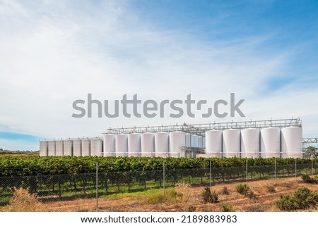 Grapevines with large wine tanks viewed from the highway in South Australia on a day