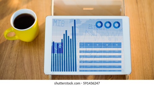 Graph chart on digital tablet with black coffee on table