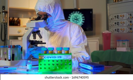 Graphic Of The Coronavirus COVID19 On A Monitor In The Background And A Virologist In Full PPE Working In His Medical Science Laboratory.