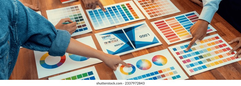 Graphic designer brainstorm logo and graphic art at busy creative studio workshop. Experiment and brainstorm color palette and pattern at workspace table for creative design. Panorama shot. Scrutinize - Powered by Shutterstock