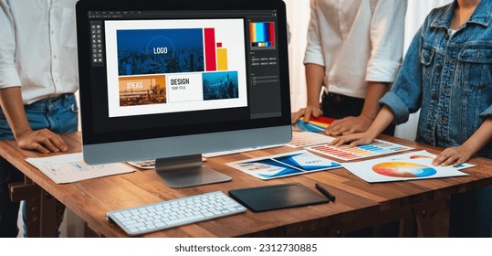 Graphic designer brainstorming logo and graphic art at busy artistic workshop, laptop display workspace. Experimenting color palette and pattern for creative design. Panorama shot. Scrutinize