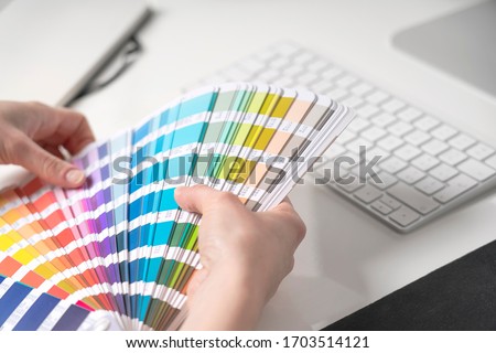 Graphic designer chooses colors from palette guide for painting and printing a new creative business work