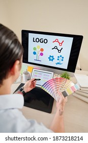 Graphic Designer With Color Palette In Hands Creating Company Logo