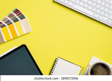 Graphic designer desk top view with RAL colors palette, tablet, notebook, cup of coffee, computer keyboard on yellow background. Flat lay, view from above. Professional creative workspace. - Powered by Shutterstock