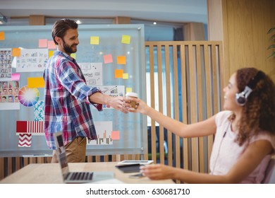 Graphic designer offering coffee to his colleague in office - Powered by Shutterstock