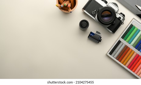 Graphic Designer Or Photographer Workspace With Retro Camera, Film, Stationery, Chalks Colour And Copy Space On White Background. Top View