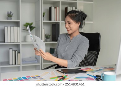 Graphic designer reviewing color drafts in modern office - Powered by Shutterstock