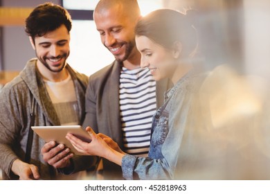Graphic designer using digital tablet with his coworker in the office
