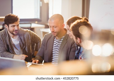 Graphic designer using digital tablet with his coworker in the office