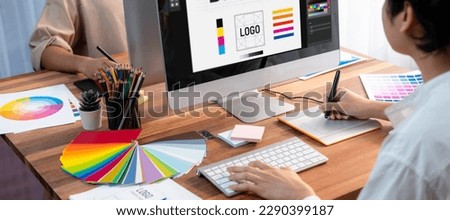 Graphic designer work on computer laptop and with graphic drawing pen while brainstorming unique design with professional graphic team in modern digital studio workplace. Panorama shot. Scrutinize