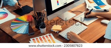 Graphic designer work on computer laptop and with graphic drawing pen while brainstorming unique design with professional graphic team in modern digital studio workplace. Panorama shot. Scrutinize
