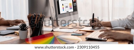 Graphic designer work on computer laptop and with graphic drawing pen while brainstorming unique design with professional graphic team in modern digital studio workplace. Panorama shot. Scrutinize