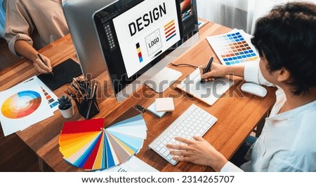 Graphic designer work on computer laptop and with graphic drawing pen while brainstorming unique design with professional graphic team in modern digital studio workplace. Panorama shot. Scrutinize