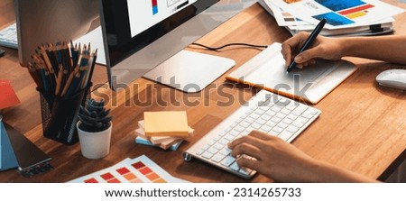 Graphic designer work on computer laptop and with graphic drawing pen while brainstorming unique design with professional graphic team in modern digital studio workplace. Panorama shot. Scrutinize