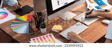 Graphic designer work on computer laptop and with graphic drawing pen while brainstorming unique design with professional graphic team in modern digital studio workplace. Panorama shot. Scrutinize