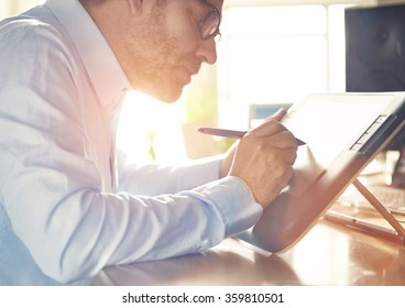 Graphic Designer working with interactive pen display, digital Drawing tablet and Pen on a computer. Smooth tracking shot with nice backlit lensflare.