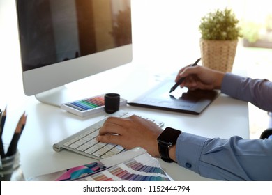 Graphic Designer Working On Modern Desktop Computer While Using Graphic Tablet At Desk In The Office