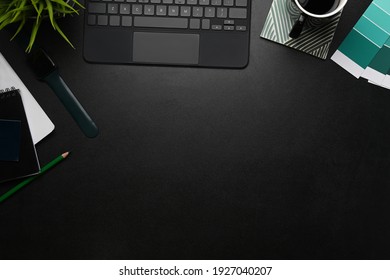 Graphic designer workplace with tablet, coffee cup, notebook, color swatch and copy space on black leather.