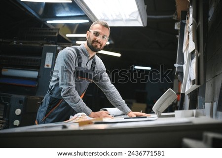 Graphic engineer or worker checking imprint quality in modern print shop.