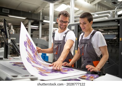 Graphic engineers or workers checking imprint quality in modern print shop.