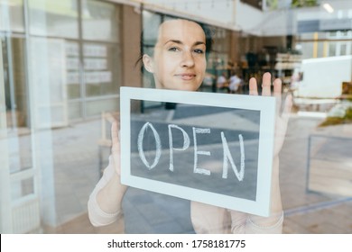 Graphic Image Of Charming French Woman Face Against Smiling Waitress Or Owner Showing Chalkboard With Open Sign Through Window. Quarantine, Coronavirus, Isolation. Back To Working Life..