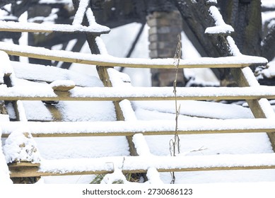 Graphic impression of burned down barn covered in snow after a blizzard snowstorm with the black wood and construction carcas contrasting against the white winter landscape